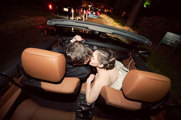 The happy couple kissing in a convertible before they leave the ceremony - photo by Houston based wedding photographer Adam Nyholt